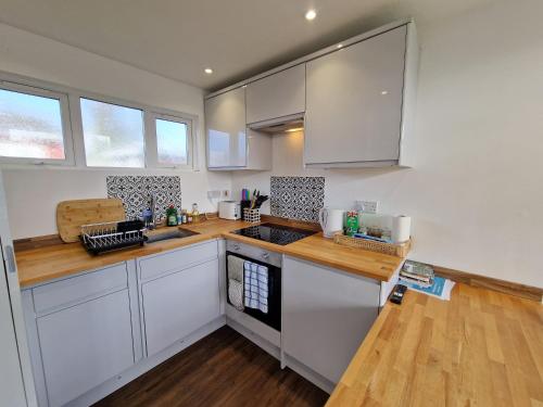 een keuken met witte kasten en een houten aanrecht bij 67 Broadside Holiday Chalet near Broads & Beaches in Stalham