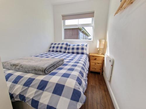 een kleine slaapkamer met een bed en een raam bij 67 Broadside Holiday Chalet near Broads & Beaches in Stalham