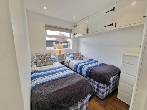 two beds in a small room with white cabinets at 67 Broadside Holiday Chalet near Broads & Beaches in Stalham