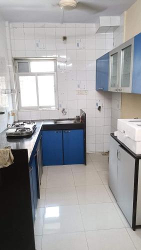 cocina con armarios azules y suelo de baldosa blanca en master bedroom A2, en Bombay