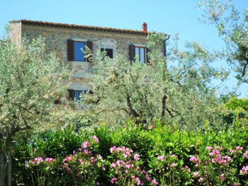 an old building behind some trees and flowers at Mezzomonte View in Impruneta