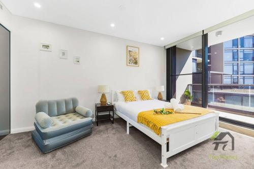 a white bedroom with a bed and a chair at Sunshine 2 Bed home in Olympic Park in Sydney