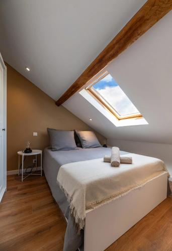 une chambre avec un grand lit avec une lucarne dans l'établissement Villa Poe-Tehani - Appartements design - Centre ville, à Vichy