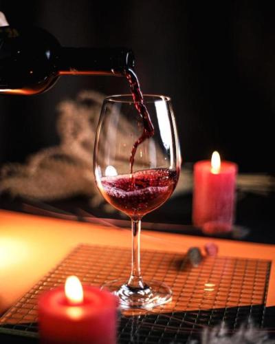 a person pouring red wine into a wine glass at Hotels-Widok Rynek - Centrum &Parking -fak VAT in Kielce