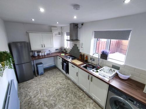a kitchen with white cabinets and a counter top at Comfortable 3 Bedrooms Leeds Beach House - Ideal for Family and Contractors - Free WIFI, Projector in bedroom and Free Parking for 2 cars in Killingbeck