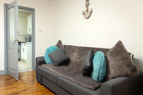 a couch with pillows on it in a living room at Comfortable 3 Bedrooms Leeds Beach House - Ideal for Family and Contractors - Free WIFI, Projector in bedroom and Free Parking for 2 cars in Killingbeck