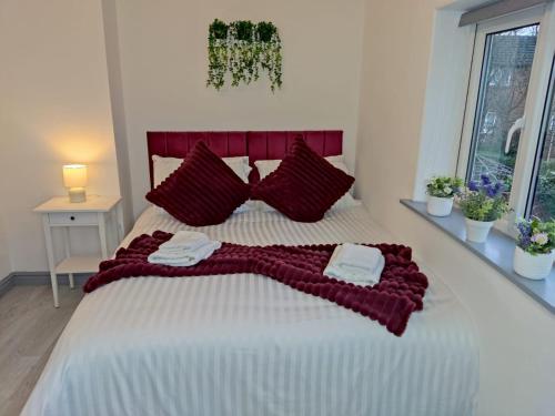a bedroom with a large bed with red pillows at Comfortable 3 Bedrooms Leeds Beach House - Ideal for Family and Contractors - Free WIFI, Projector in bedroom and Free Parking for 2 cars in Killingbeck