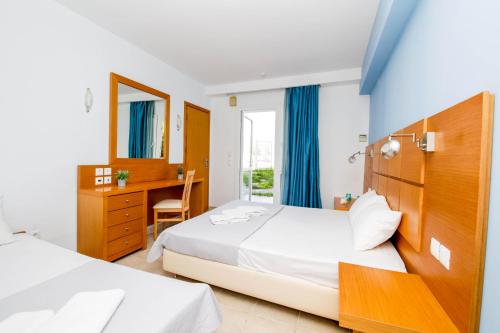 1 dormitorio con 2 camas, escritorio y ventana en Haris Hotel, en Chaniotis