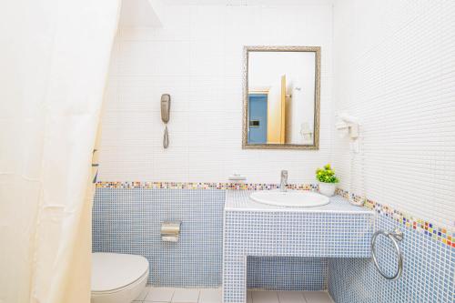 a bathroom with a toilet and a sink and a mirror at Haris Hotel in Hanioti