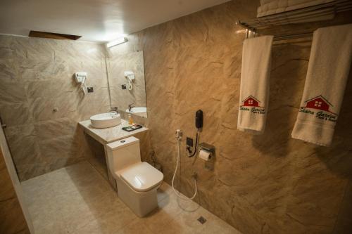 a bathroom with a toilet and a sink and a phone at Shaira Garden Hotel & Resorts in Nārāyanganj