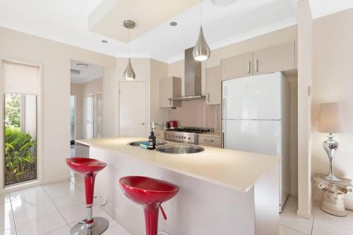 a kitchen with red stools and a white counter top at Impeccable Modern 1 Bedroom Apartment ~ Taringa in Brisbane