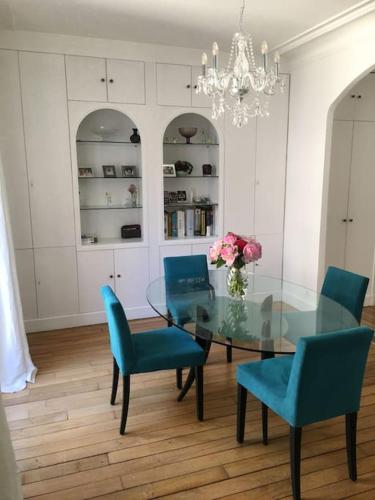 une salle à manger avec une table en verre et des chaises bleues dans l'établissement Elégant 4-room apartment near Arc de Triomphe and Palais des Congrès, à Paris