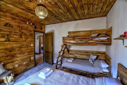 a bedroom with two bunk beds and a wooden wall at Вила Приказка in Zar-Kalojan