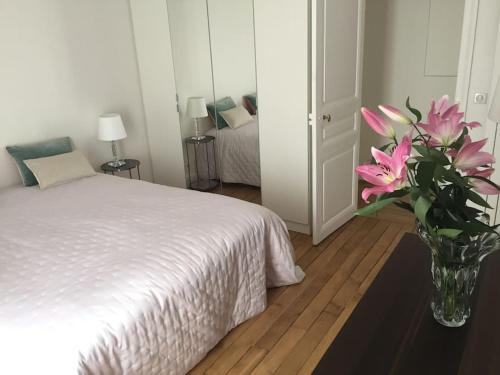 - une chambre avec un vase orné de fleurs roses dans l'établissement Elégant 4-room apartment near Arc de Triomphe and Palais des Congrès, à Paris