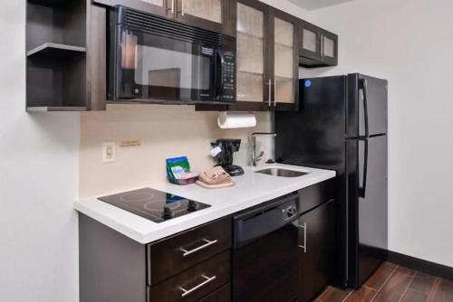 a kitchen with a sink and a black refrigerator at Candlewood Suites Beaumont by IHG in Beaumont