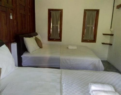 a bedroom with two beds and two windows at Mettaloka Guesthouse in Magelang