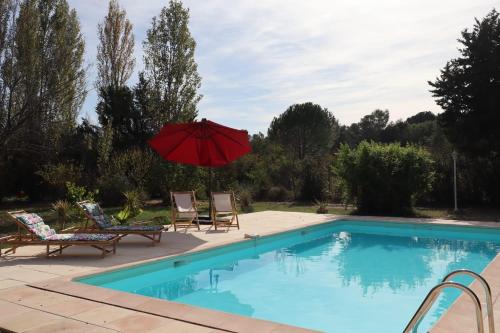 - une piscine avec un parasol rouge et 2 chaises dans l'établissement La Maison de Blu, à Lorgues