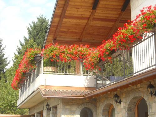 a balcony with red flowers on a building at La Stella delle Alpi in Vico Canavese