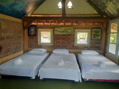 three beds in a room with a brick wall at Mettaloka Guesthouse in Magelang
