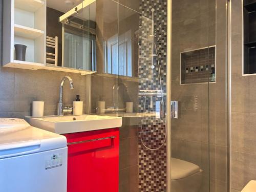 y baño con lavabo y ducha con armarios rojos. en Carla's Residences F1 Hyper Centre, en Aix-les-Bains