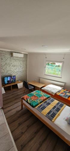 a room with two beds and a table and a window at Apartmani Roki in Tuzla