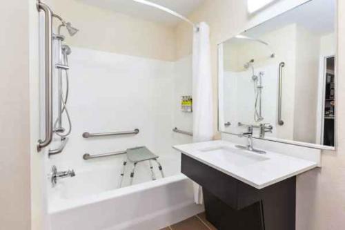 a white bathroom with a sink and a bath tub at Candlewood Suites Beaumont, an IHG Hotel in Beaumont