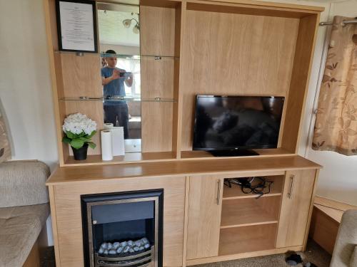 a entertainment center with a tv and a fireplace at Plot 203 paris in Rhyl