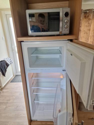 a microwave sitting on top of a refrigerator at Plot 203 paris in Rhyl