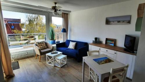 a living room with a blue couch and a window at Haus Panorama - Kleines Sternchen in Grömitz
