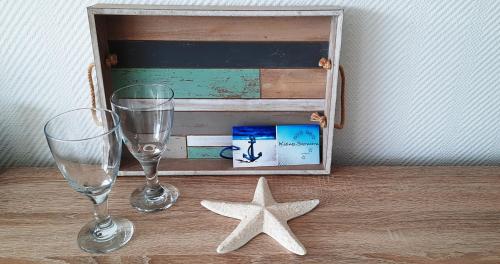two glasses and a wooden box with a starfish on a table at Haus Panorama - Kleines Sternchen in Grömitz