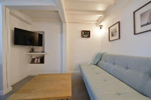a living room with a blue couch and a tv at LE PETIT BATEAU - NEW cosy/charming studio/mezzanine for 3 - AC/WIFI in Antibes