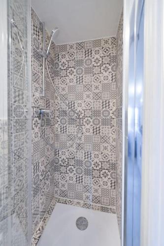 a bathroom with a shower with a tile wall at LE PETIT BATEAU - NEW cosy/charming studio/mezzanine for 3 - AC/WIFI in Antibes