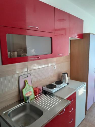 a kitchen with red cabinets and a sink at Perper in Sutomore