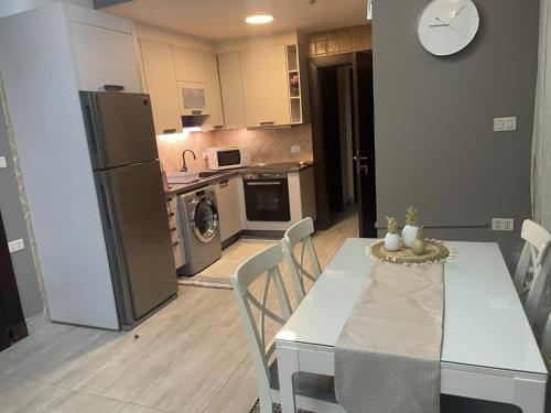 eine Küche mit einem Tisch und Stühlen sowie eine Küche mit einem Kühlschrank in der Unterkunft Abdoun apartment in Amman