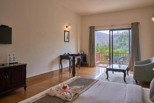 Schlafzimmer mit einem Bett, einem Schreibtisch und einem Balkon in der Unterkunft The Hunting Lodge Resort Udaipur - Villas & Pool in Dabok