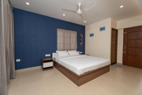een slaapkamer met een bed en een blauwe muur bij Lumiere Premium Apartments in Trivandrum