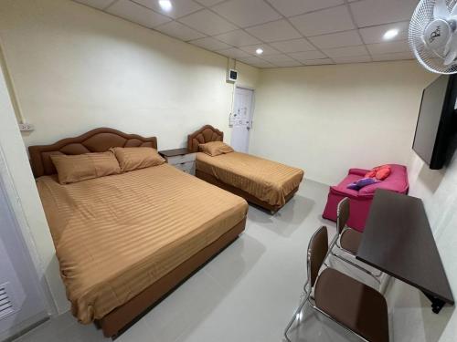 2 camas en una habitación con TV y sillas en Nopphadon Hotel en Lat Krabang