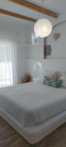 a large white bed in a white room with a window at Seva's House in Psinthos