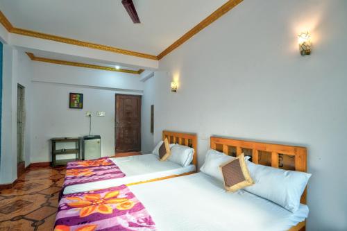 Om Sai Guest House في كالانغيُت: غرفة نوم بسريرين مع شراشف بيضاء