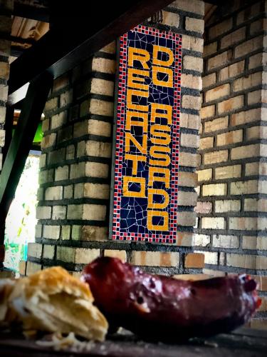a sign on the side of a brick wall with a sausage at Hotel Natur Campeche in Florianópolis