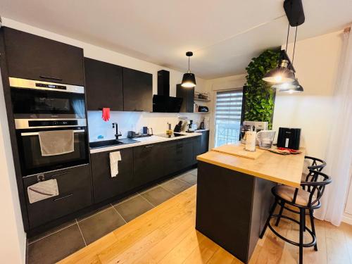 eine Küche mit schwarzen Schränken und einer hölzernen Arbeitsplatte in der Unterkunft JO Paris 2024 in Saint-Ouen
