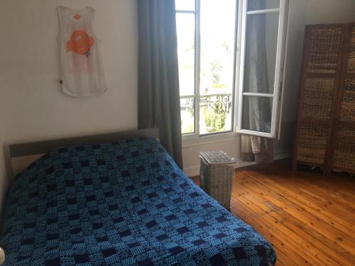 une chambre avec un lit avec une couette bleue et une fenêtre dans l'établissement Appartement proche de Paris, à Deuil-la-Barre