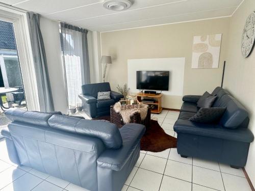 a living room with blue couches and a tv at Bohemien Resort 46 in Sint Maartensvlotbrug