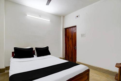 - une chambre avec un lit blanc et des oreillers noirs dans l'établissement SPOT ON HOTEL MEERa, à Farakka