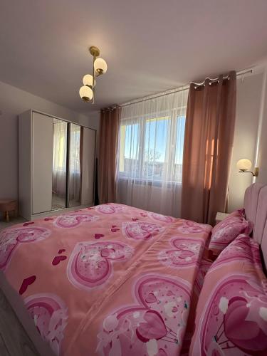 a bedroom with a pink bed and a large window at Apartament pe pietonala nr1 in Hunedoara