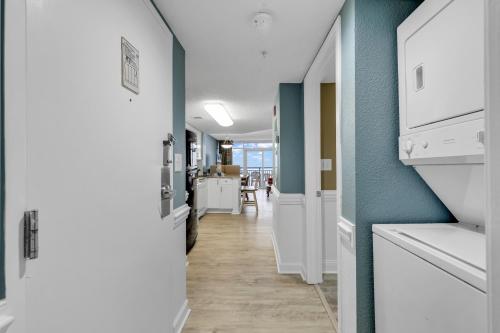 a kitchen with blue walls and a hallway with white appliances at Atlantica Resort Condo Oceanfront Close to the beach in Myrtle Beach