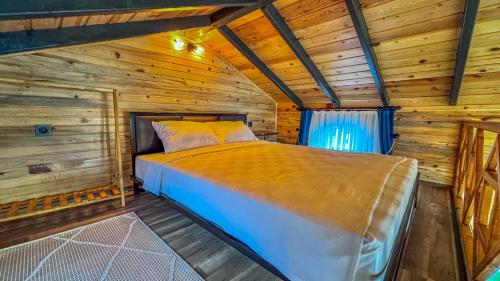 um quarto com uma cama num chalé de madeira em Tringo Bungalov em Ayvalik
