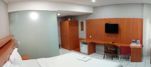 1 dormitorio con 1 cama y escritorio con TV en GUEST HOUSE UPY en Ngabean