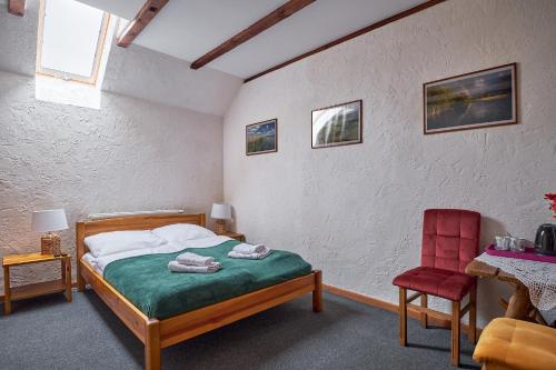 1 dormitorio con 1 cama y 1 silla roja en Karczma Zacisze en Krutyń
