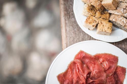 zwei Teller Essen auf einem Tisch mit Fleisch und Brot in der Unterkunft Agritur Calvola in Tenno